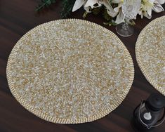 two round placemats sitting on top of a wooden table next to a vase with flowers