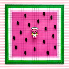 a pink and green square with black dots on it that has a piece of food in the middle