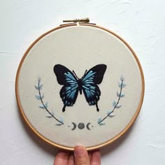 a hand is holding a small embroidered butterfly