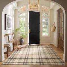 an archway leading into a living room with a rug on the floor and a black door