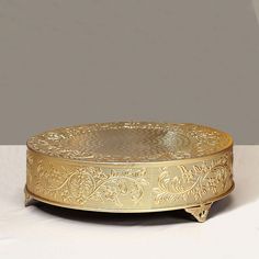 an ornately decorated gold plate on a white tableclothed surface with a gray background