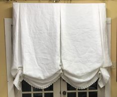 a white curtain hanging on the side of a window