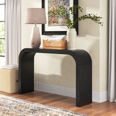 a black console table with two vases and a lamp on it in front of a window