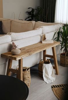 a wooden bench sitting in the middle of a living room next to a white couch