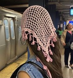 a woman wearing a pink crochet hat at a train station