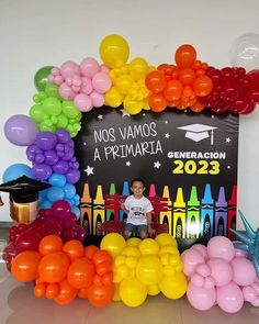 a young boy sitting in front of a sign surrounded by balloons and streamers that read, nos vamos a preimariata generale 2013