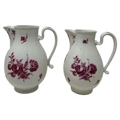 two white vases with purple flowers painted on them