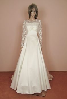 a mannequin dressed in a white wedding dress with long sleeves and laces