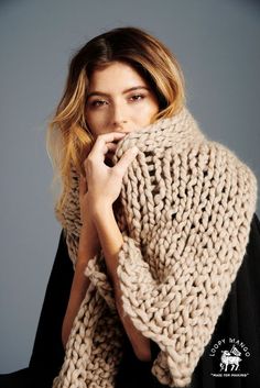 a woman wearing a knitted shawl with her hands on her face