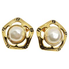 Elevate your style with the Fendi 1980s Gold Tone FF Pearl Earrings – a beautiful blend of classic elegance and iconic Fendi design. These stunning yellow gold plated earrings feature subtle black 'FF' Fendi logos throughout, encasing exquisite synthetic pearls. Designed in a convenient clip-on style, these earrings are as timeless as they are versatile, effortlessly transitioning from day to night and pairing seamlessly with just about anything in your closet. The delicate interplay of gold-ton Luxury Gold-tone Gold-plated Clip-on Earrings, Luxury Timeless Yellow Gold Clip-on Earrings, Luxury Elegant Pearl Clip-on Earrings, Fendi Earrings, Chanel Heels, Gucci Dress, Versace Handbags, Fendi Logo, Timeless Luxury