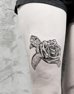 a woman's thigh with a tattoo of a sea turtle and a rose on it