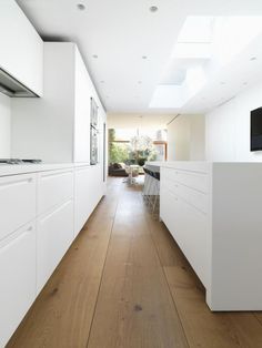 an empty kitchen with white cabinets and wood flooring is seen in this image from the hallway to the living room