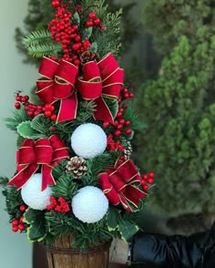 a christmas tree made out of golf balls and evergreens with red bows on it