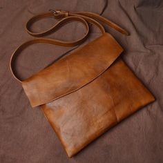 a brown leather purse sitting on top of a bed