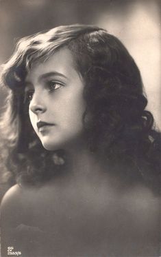 an old black and white photo of a woman with curly hair looking off to the side