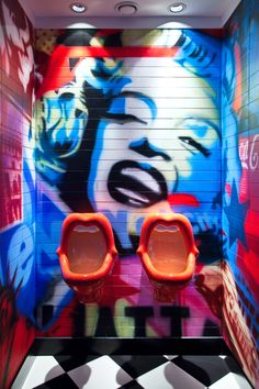 two urinals are in front of a colorful wall with marilyn monroe's face on it