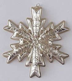 a silver snowflake ornament on a white background