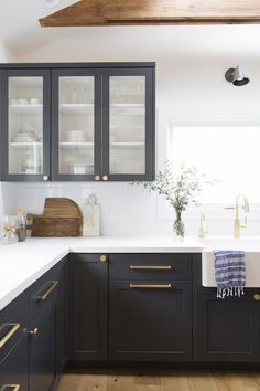 a kitchen with black cabinets and white counter tops, gold pulls on the cabinet doors