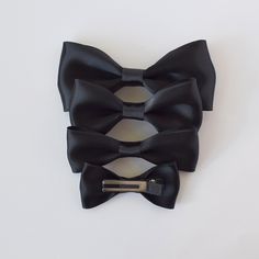 Get ready to impress with our Black Satin Bow-Tie. With four available sizes, these bow-ties are suitable for newborns all the way up to men. They're a must-have for weddings, holiday photoshoots, and any special occasion. Simply slide the clip over the top button and you're all set! • Satin ribbon• Bow-tie size • XS-0-6mos • Small 6mos.-4yrs. • Medium 4-12yrs • Large teen/adult• Handmade in the USA• Small women-owned business *Please note that bows are handcrafted and may vary slightly in size and look. Measurements are approximate. **NEVER leave children unattended or sleeping while wearing ANY hair accessories from Your Final Touch. Products may contain parts that can pose a choking hazard or strangulation. Formal Adjustable Ribbon Hair Accessories, Black Bow Tie For Wedding, Formal Hair Accessories With Bow, Black Bow Hair Accessories For Wedding, Trending Colors, Clip Design, Satin Ribbon Bow, Tie Gifts, Small Women