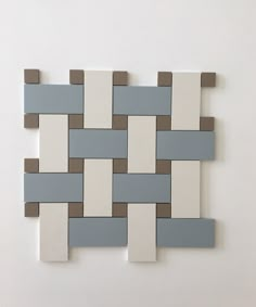 a white and gray tile wall with some squares on the bottom one is made out of ceramic tiles