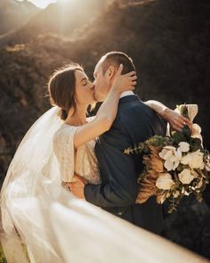 a bride and groom kissing in front of the sun