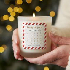 a person holding a candle with a calendar on it in front of a christmas tree