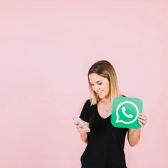 a woman holding a green whatsapp sign and a cell phone in her hand