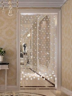 a white table sitting in front of a door with lights on the side and a chandelier hanging from it's ceiling