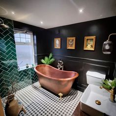 a bathroom with black and white checkered flooring, gold bathtub in the center