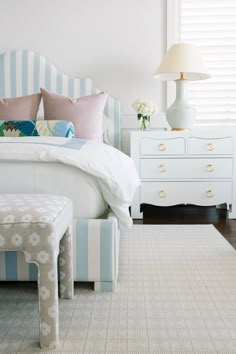 a bedroom with blue and white striped bedding, two nightstands, and a bench