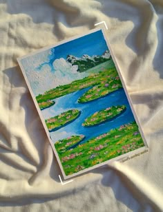 a painting on a white sheet with water lilies in the grass and clouds above it