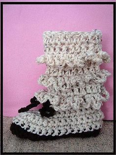 a pair of crocheted boots sitting on top of a pink surface next to a wall