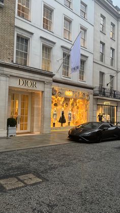 a black sports car is parked in front of a dior store on the street