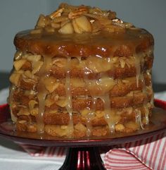 a cake covered in caramel drizzle and nuts on top of a red plate