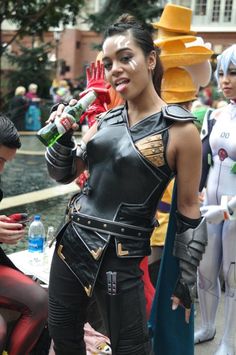 a group of people dressed up in costumes and holding drinks at an outdoor event with one woman drinking from a bottle