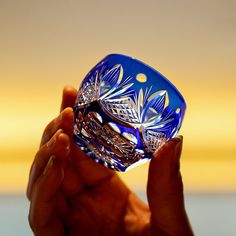 a hand holding a blue glass object in it's palm