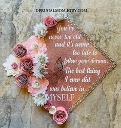 a pink graduation cap with flowers on it and the words, you're never too old and it's never too late to follow your dreams