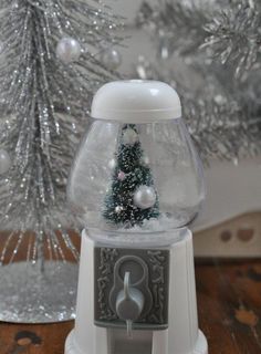 a snow globe sitting on top of a wooden table next to a silver christmas tree