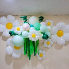 balloons and flowers are arranged in the shape of white daisies on a beige surface