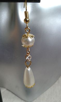 earrings made with ivory pearls and a white rhinestone connector and gold metal dimensions: 4.5 cm long White Metal Earrings With Pearl Chain, White Pearl Chain Earrings In Metal, Gold Pearl Charm Clip-on Earrings, Gold Clip-on Pearl Earrings With Pearl Charm, White Pearl Charm Earrings In Metal, Gold Clip-on Earrings With Pearl Charm, White Pearl Earrings With Metal Charm, White Metal Clip-on Earrings With Pearl Drop, White Pearl Clip-on Earrings With Pearl Charm