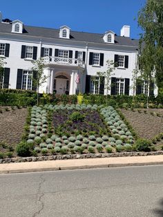 a large white house sitting on the side of a road next to a lush green hillside