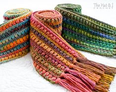 three multicolored crocheted baskets sitting on top of a white table next to each other