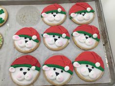 decorated cookies in the shape of teddy bears with hats and noses are on a baking sheet