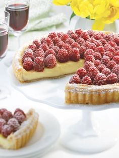 a tart with raspberries and powdered sugar on top sits on a white plate