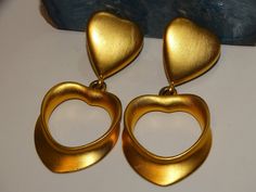 "The earrings are gold-tone metal featuring two hearts, size 2.5\" inches tall x 1 1/4\" inch wide, weight 33.8 grams in excellent condition." Gold Heart-shaped Clip-on Earrings, Vintage Gold Heart-shaped Earrings, Vintage Gold Heart Earrings, Gold Double Heart Metal Earrings, Gold Metal Double Heart Earrings, Gold Clip-on Heart Earrings For Valentine's Day, Vintage Gold Heart Earrings For Party, Vintage Gold Double Heart Earrings, Gold Double Heart Vintage Earrings