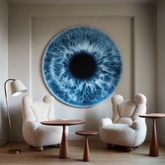 two chairs and a table in front of a large blue eye print on the wall