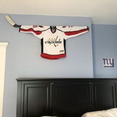 a hockey jersey hanging on the wall above a bed in a room with blue walls