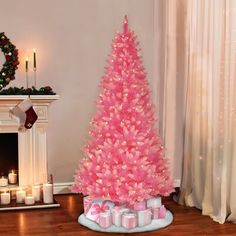 a pink christmas tree in a living room with presents on the floor next to it