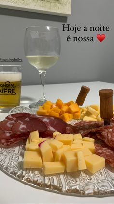 an assortment of cheeses and meats on a plate with a glass of wine