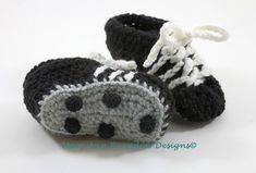 a pair of black and white crocheted baby shoes